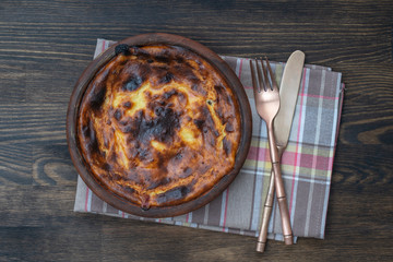 Sweet cottage cheese casserole with raisins and semolina on wooden table. Ceramic bowl with baked cottage cheese casserole , closeup, top view