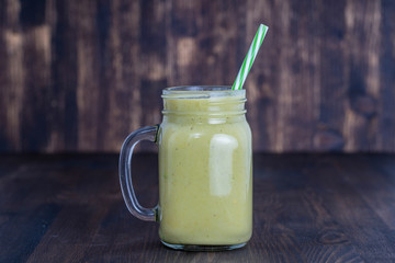 Fresh green smoothie from avocado, kiwi, banana and honey in glass mug on wooden background, closeup. Concept of healthy eating