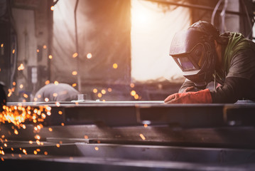 A welder with a welding machine works in a factory