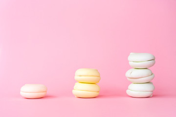 Peach, yellow and green color marshmallows on a pastel pink background. Concept of classification and growth.