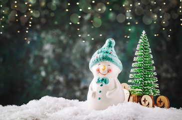 Merry Christmas and happy New Year composition with copy space. Little snowman carries Christmas tree from fairy forest to home. Winter festive background