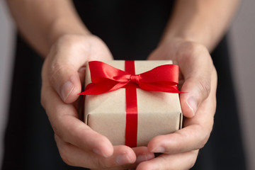 Man is holding brown gift box with red ribbon in two hands for special day,suchas Christmas day ,Valentine day