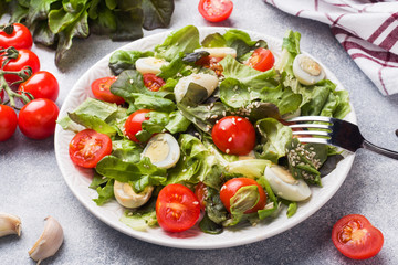 Fresh salad with tomatoes and quail eggs and lettuce.