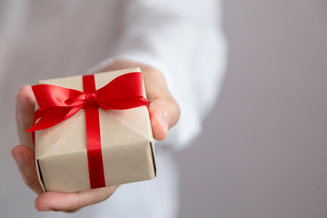 Man is holding brown gift box with red ribbon in two hands for special day,suchas Christmas day ,Valentine day