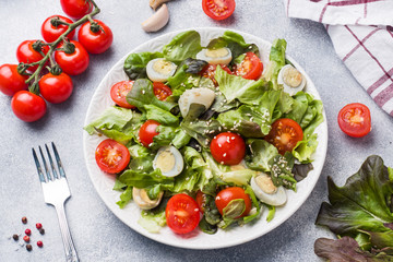 Fresh salad with tomatoes and quail eggs and lettuce.