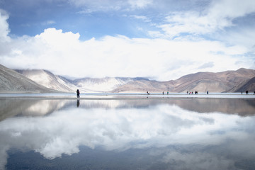 LEH LADAKH, INDIA - JUN19, 2018: Reflections of high mountain with white cloud and blue sky on the Pagong lake, Leh Ladakh, India.