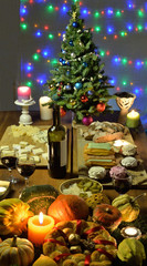 Christmas table with festive food, burning candles and a fir tree decorated