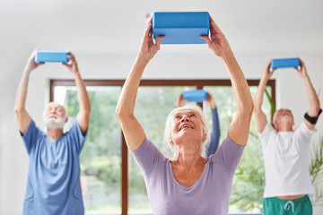 Seniors do back training with a yoga block