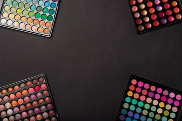 Colorful eyeshadow palettes on black background with a place for your copy space. Flat lay. Top view