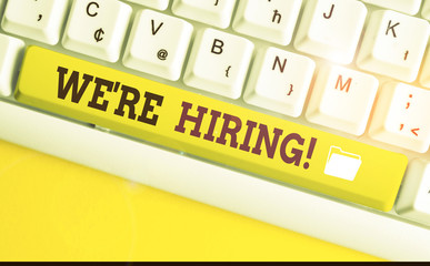 Text sign showing We Re Hiring. Business photo text process of reviewing applications and finding candidates White pc keyboard with empty note paper above white background key copy space