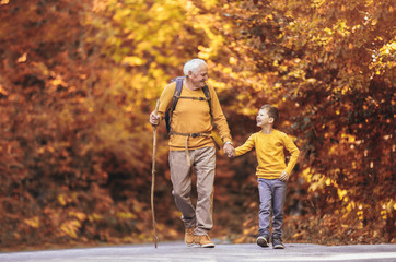 Grandfather and grandson hiking together in autumn park