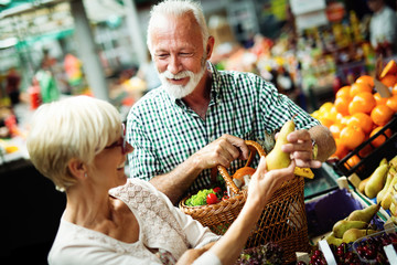 Mature shopping couple with basket on the market. Healthy diet.