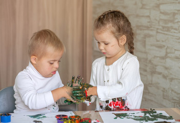 Little children paint with paints. The kids got their hands dirty in gouache. A cute girl and a boy...