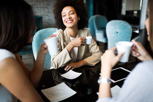 Successful attractive women friends chatting in cafe during coffee break
