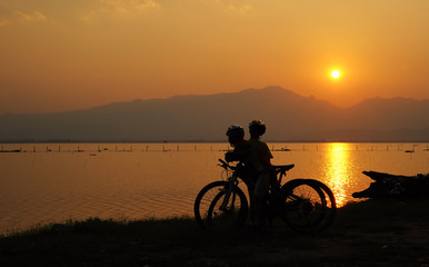 Fototapeta na wymiar Two biker stop at the lake to see beautiful sunset 
