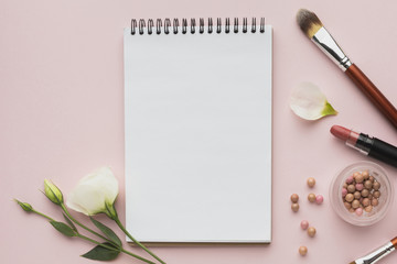 Top view arrangement with make-up products and notebook