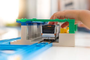 Close up of a little child's hands playing, assembling the colorful plastic railway track. Educational hands-on toys, Kids Thinking skills, Brain development. Japanese, JR, Popular Model train.