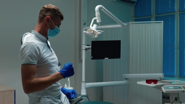 funny young handsome doctor dentist dancing happily near his working place wearing medical gloves and mask in his office