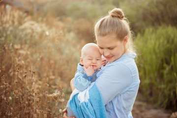 Fototapeta premium Portrait of beautiful young mother holding her baby toddler. Happy family, mother and child play concept