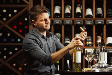 Sommelier in process of opening white wine bottle