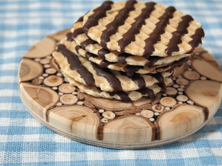 Chocolate cookies on wooden plate on table with blue pattern background. Horizontal close up view.