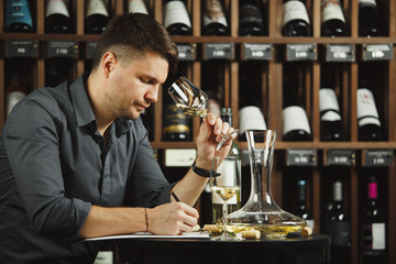 Sommelier degustating white wine poured in glass
