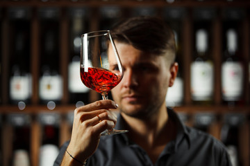 Bokal of red wine on background, male sommelier appreciating drink