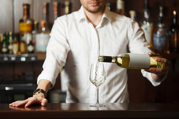 Sommelier in shirt pouring white wine into glass