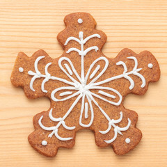 Close-up of sweet Christmas gingerbread snowflake cookie on wooden background