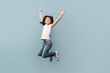 Happy little girl jumping high shooting in professional studio