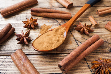 Fragrant spices cinnamon sticks and ground, star anise on wooden background.