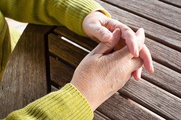 指を組んでいる高齢女性