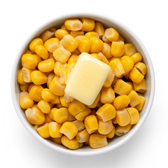 Canned sweet corn with a knob of butter in a white ceramic bowl isolated on white. Top view.