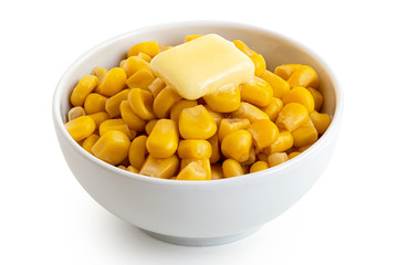 Canned sweet corn with a knob of butter in a white ceramic bowl isolated on white.