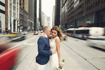 Beautiful bride in a long white dress. Handsome fiance in a blue suit. Couple in a big city