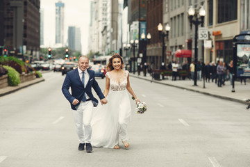 Beautiful bride in a long white dress. Handsome fiance in a blue suit. Couple in a big city