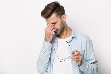 Tired millennial man take off glasses suffering from headache