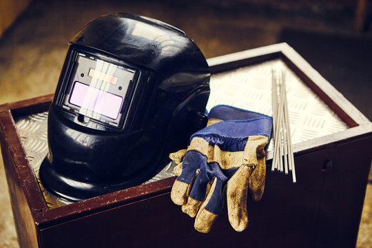 Welding mask, gloves, and electrodes on table.
