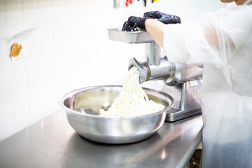 Grinding cheese through a grinder. Work in a food factory
