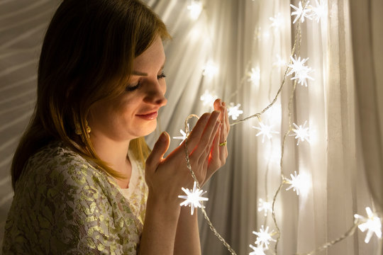 Portrait of a beautiful young white woman with brown hair holding an illuminated star shaped christmas chain of lights in her hands