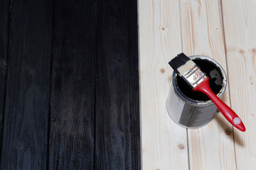 painting a wooden Board in black. a jar of black paint and a brush.