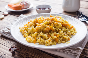 Vegetarian Oriental pilaf with rice and vegetables on a wooden table.