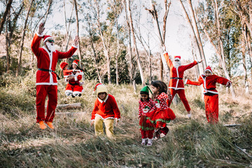 Group of people disguised to christmas jumping on the forest