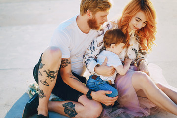 Beautiful red-haired woman with her husband and a wonderful son sitting on a summer beach on the sand