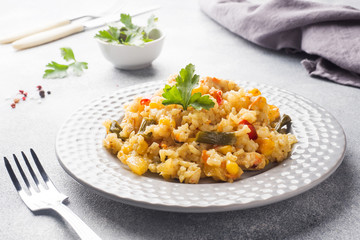Pilaf with vegetables and chicken in a gray plate on a light background.