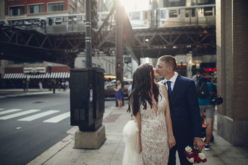 Elegant wedding couple walking in a summer city. Man in a blue suit. Woman in a white elegant dress