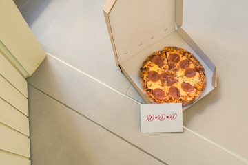 Open box of pizza and card with text: xo-xo on home doorstep on front porch. Delivery. Concept