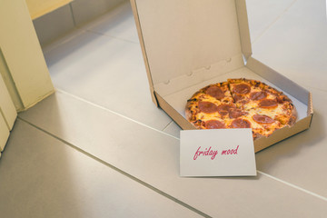 Open box of pizza and card with text: friday mood on home doorstep on front porch. Delivery. Concept