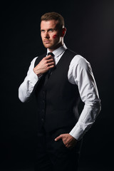 boss wth a lip mark on his cheek touching his tie, young businessman cannot concentrate on work after sleepless night , close up portrait, isolated black background, studio shot