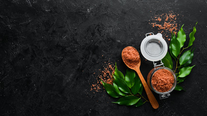 Brown sea salt in a spoon. On a black stone background. Spa treatments. Top view. Free copy space.